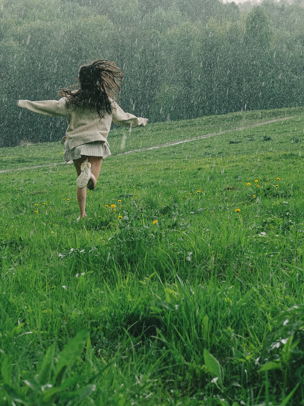 a person running in a grass field while raining